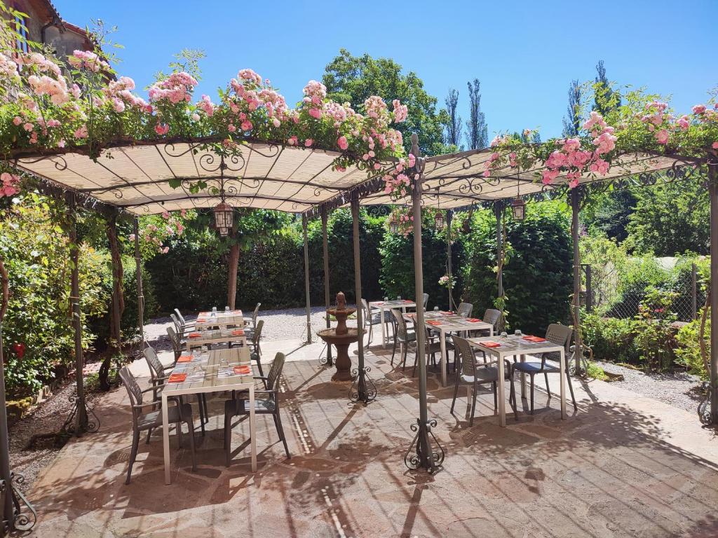 a patio with tables and chairs under a pergola with flowers at Le Relais de Ceilhes in Ceilhes-et-Rocozels