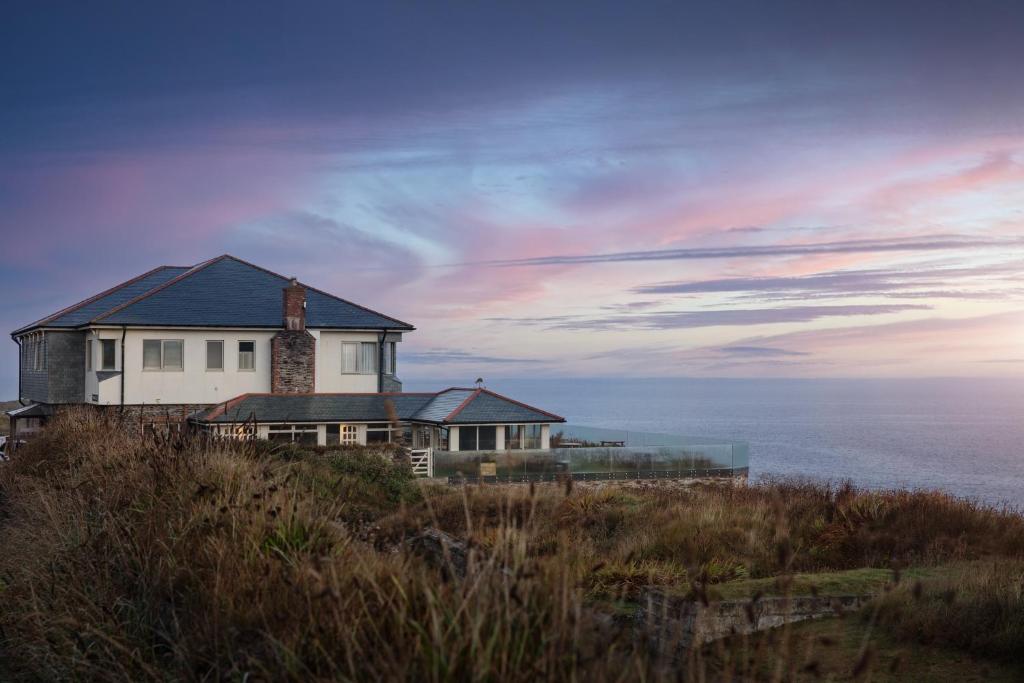 uma casa no topo de uma colina com o oceano em The Lewinnick Lodge em Newquay