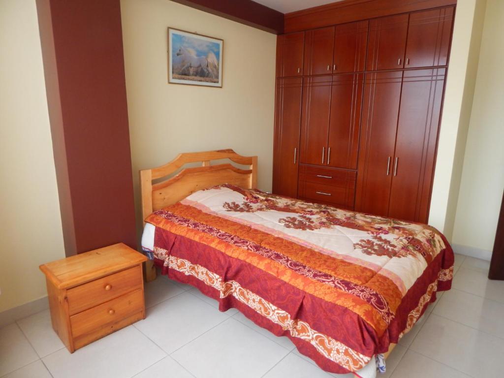 1 dormitorio con 1 cama y armario de madera en Comodo y centrico, en Ambato