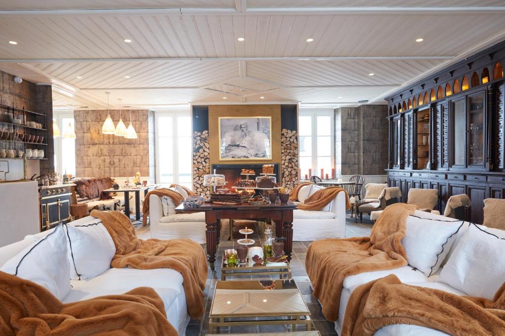 a living room with white couches and a table at Grand Hotel Soleil d'Or in Megève