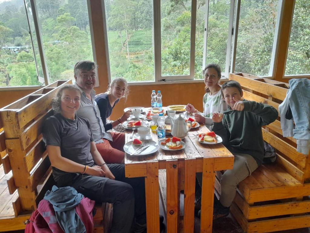 a group of people sitting around a wooden table at Water Side Guest in Adams Peak