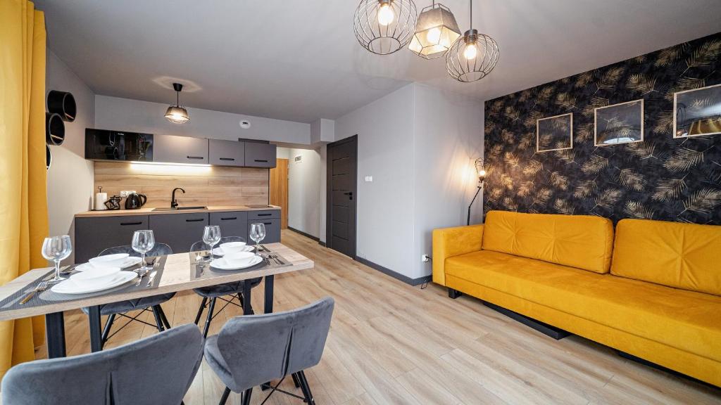 een woonkamer met een gele bank en een tafel bij Apartamenty Sun & Snow Resorts H Białka Tatrzańska z sauną in Białka Tatrzanska