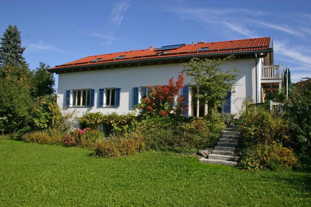 uma casa branca com um telhado vermelho e um quintal em Ferienwohnung Neelsen em Aschau im Chiemgau