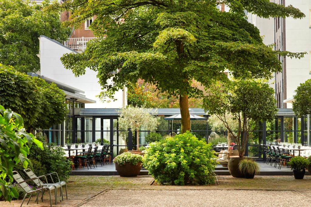 a courtyard with tables and chairs and a tree at Pulitzer Amsterdam in Amsterdam