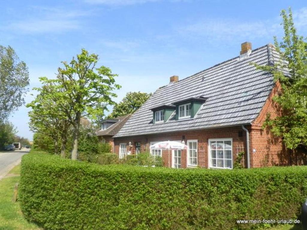 a red brick house with a black roof at Haus 94- Whg 2 in Oldsum