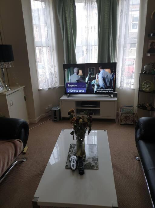 a living room with a tv and a table with flowers on it at The Havens in Liverpool