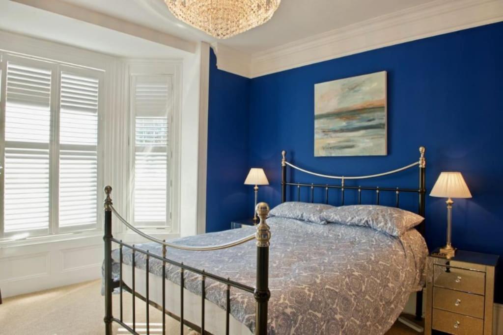 a bedroom with a bed with blue walls and a chandelier at Malvern House in Deal