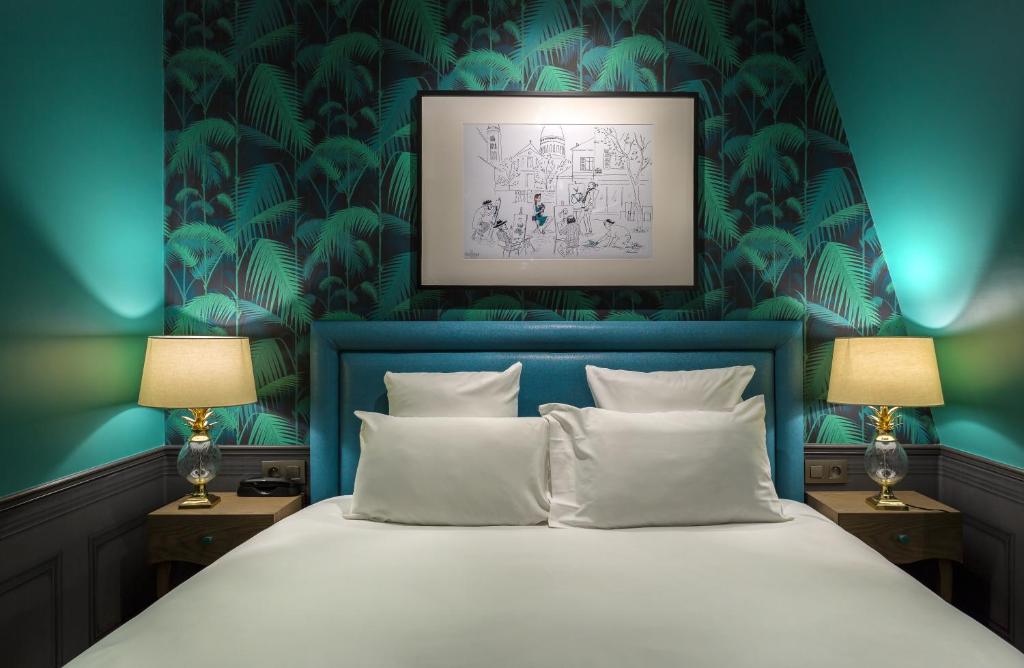 a bedroom with a bed with a blue head board at Hôtel La Parizienne - Proche Montparnasse in Paris