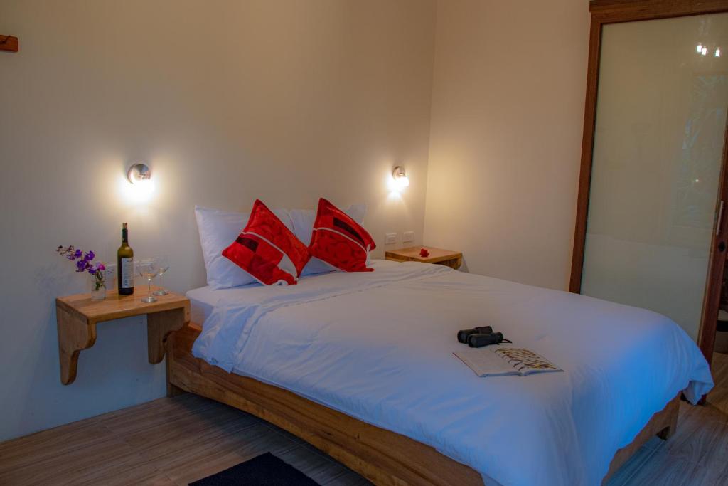 a bedroom with a large white bed with red pillows at Cabañas Armonía y Jardín de Orquídeas in Mindo