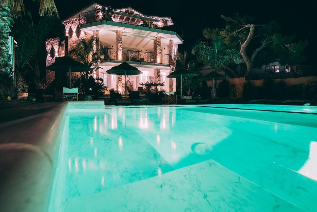 a swimming pool in front of a house at night at Villa Aquamarina Pintadera Rossa in Porto Pino