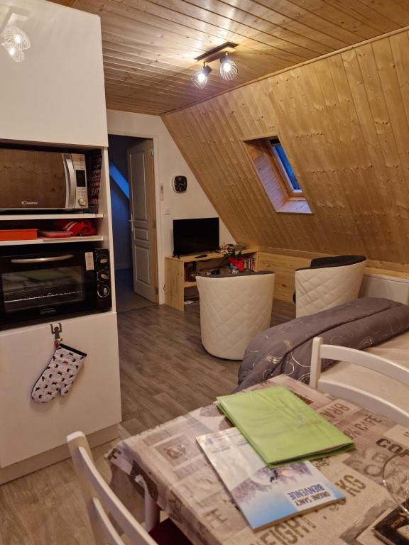 cocina y sala de estar con mesa y microondas en la maison des fleurs studio en Le Mont-Dore