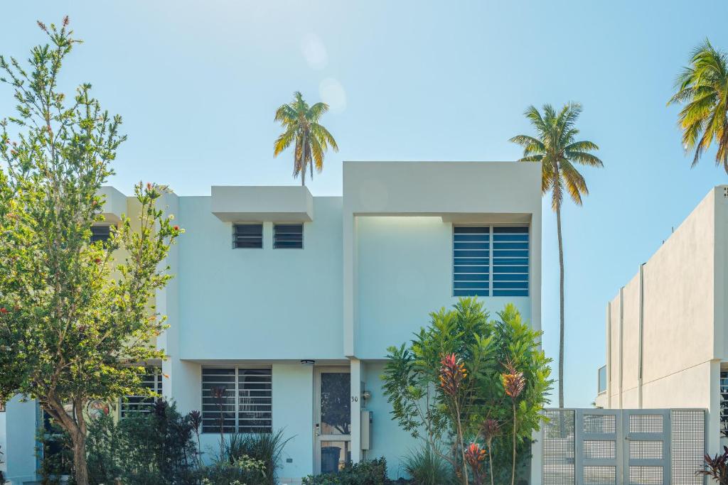 um edifício branco com palmeiras em frente em Modern Beach Walk at Puerto Bahia #30 em Rincon