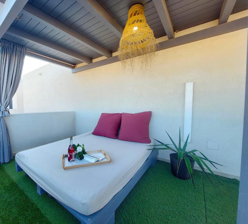 a bedroom with a bed with pink pillows and a plant at Deep Blue Cotillo II by Sea You There Fuerteventura in Cotillo