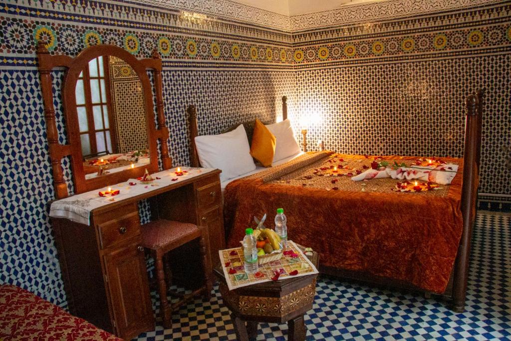 a bedroom with a bed and a table and a mirror at Riad Baba in Fez