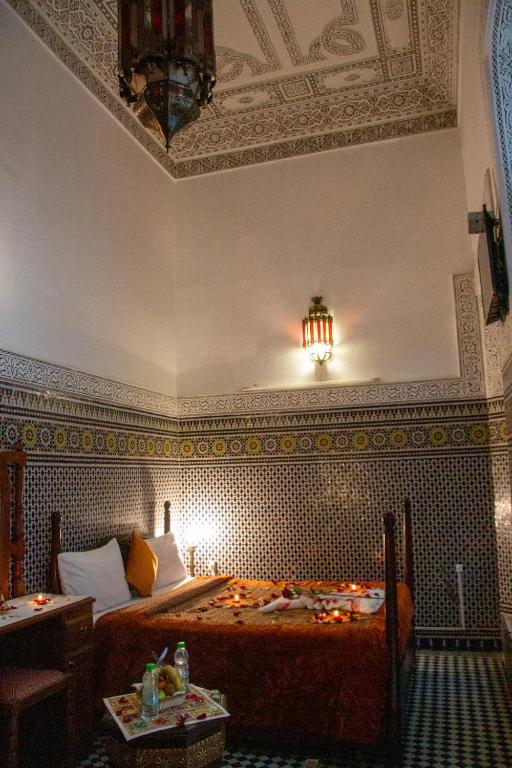 a bedroom with a bed and a chandelier at Riad Baba in Fez