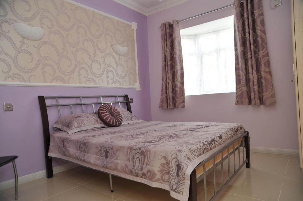 een slaapkamer met een bed met paarse muren en een raam bij Apsara Villas in Flic-en-Flac