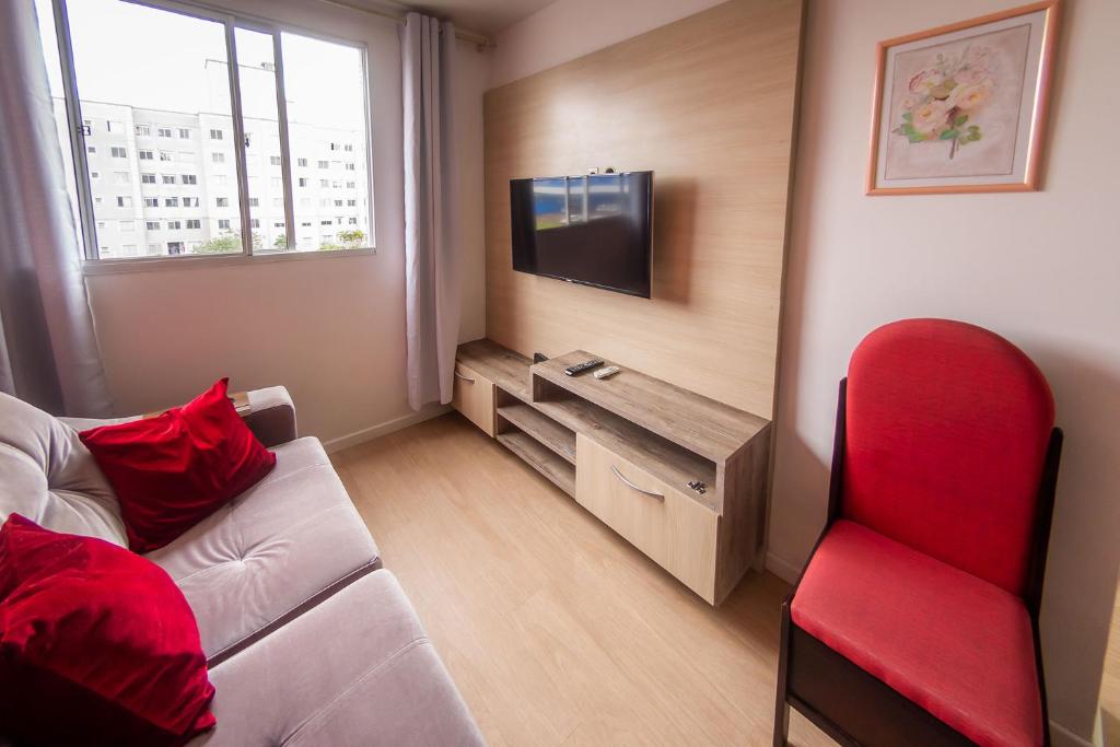 sala de estar con sofá y silla roja en Apto com Wi Fi e otima localizacao em Curitiba PR, en Curitiba