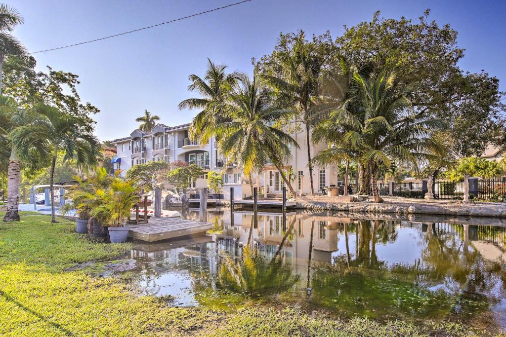 a house with palm trees and a pond at Fort Lauderdale Condo with Patio, Near Canal! in Fort Lauderdale
