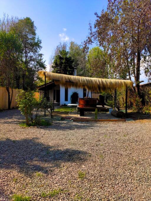 uma casa com telhado de palha e um banco à frente em Moderna Cabaña con tinaja caliente em Pirque