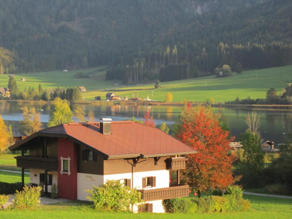 a house with a red roof next to a lake at Seehaus Verena in Weissensee