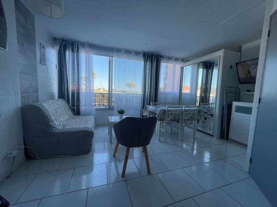 uma sala de estar com um sofá e uma mesa de jantar em Superbe appartement 6 personnes avec piscine secteur Richelieu, à 400m de la plage et à 650m du centre port em Cap d'Agde