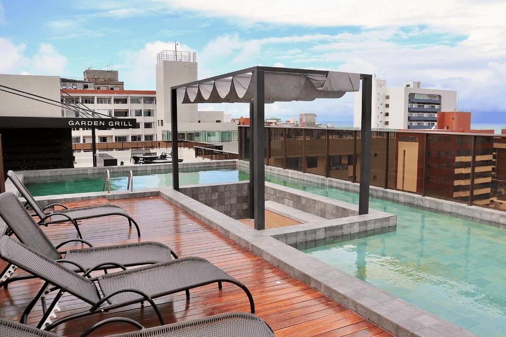 un balcón con sillas y una piscina en un edificio en Mardisa Design em Cabo Branco por Carpediem, en João Pessoa