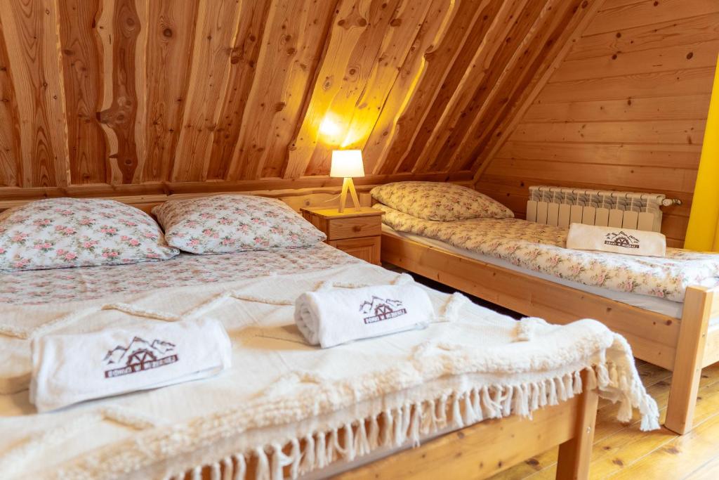 two beds in a room with wooden walls at Domki w Mizernej, Mizerna 38 nad Jeziorem Czorsztyńskim in Kluszkowce