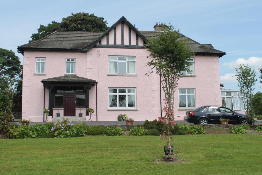 a pink house with a car parked in front of it at Riversdale Farm B&B in Ballinamore