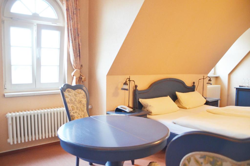 Schlafzimmer mit einem Bett, einem Tisch und einem Fenster in der Unterkunft Hotel Alt-Karow in Berlin