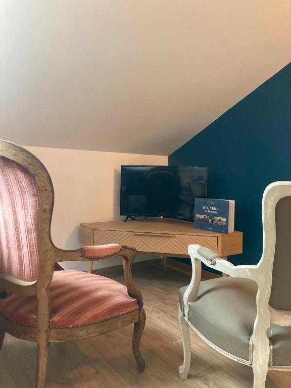 a living room with two chairs and a television at Chambre triple proche plage in Lancieux