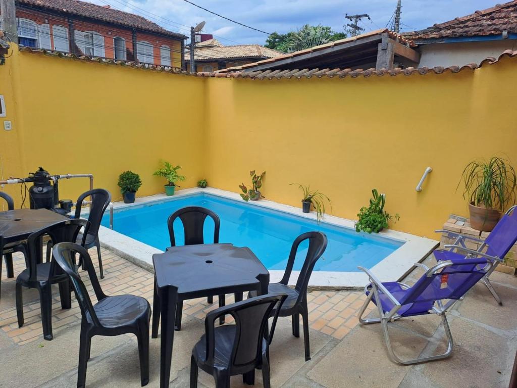 un patio con mesas y sillas junto a una piscina en Do charme, en Búzios
