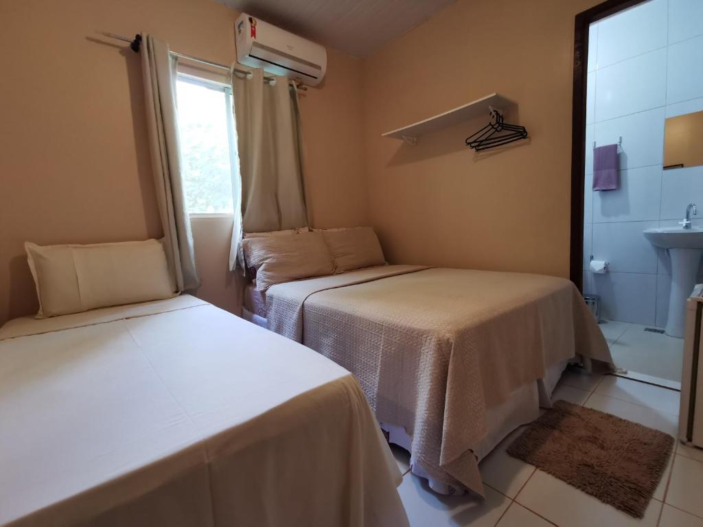 two beds in a room with a window at Casa do Anjo in Fernando de Noronha