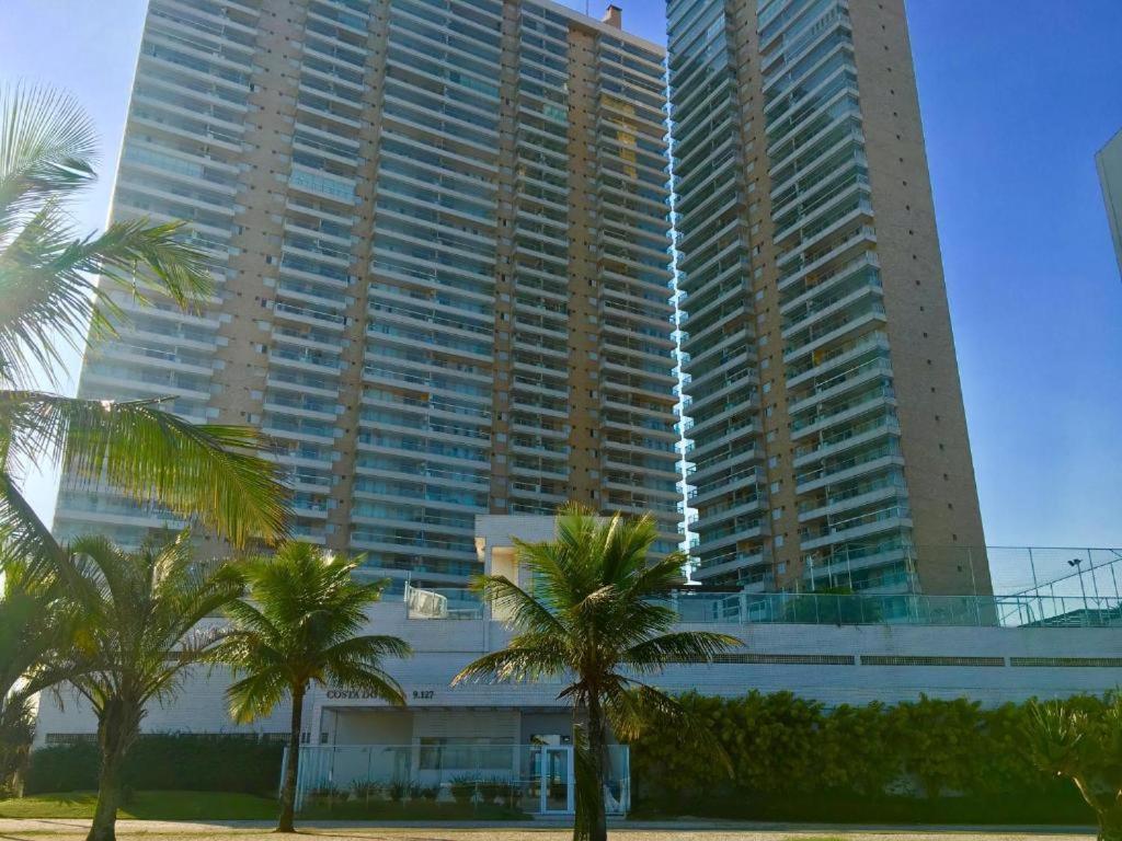 een groot gebouw met palmbomen ervoor bij Lindo Apto Pé na areia Frente para Mar in Praia Grande