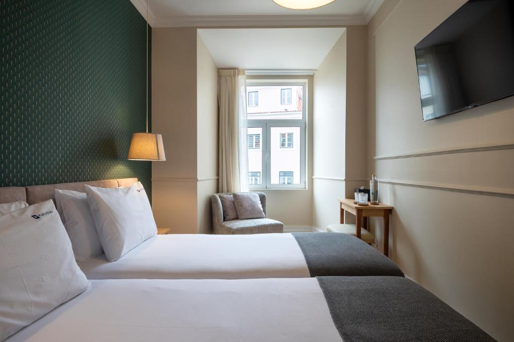 Habitación de hotel con cama y silla en Rossio FLH Suites en Lisboa