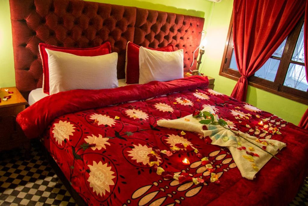 a bedroom with a red bed with a red comforter at Riad Baba in Fez
