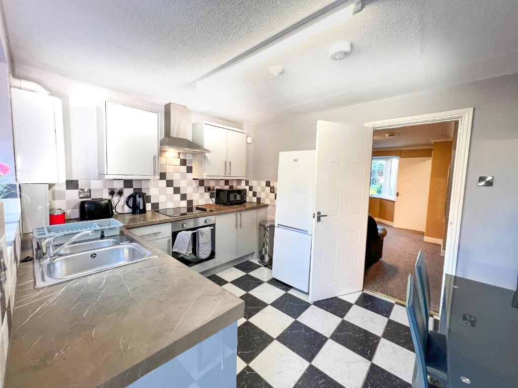 a kitchen with white cabinets and a checkered floor at Taylor Close in Fishtoft
