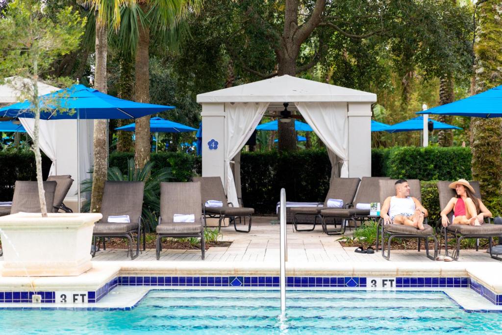 two people sitting in chairs next to a swimming pool at Omni Orlando Resort at Championsgate in Kissimmee