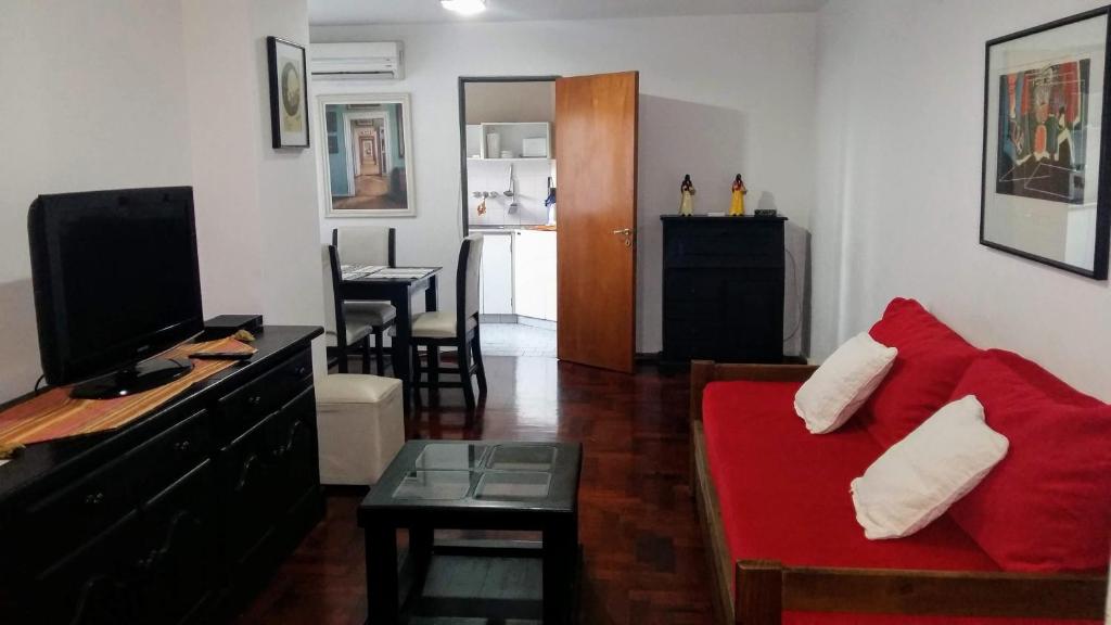 a living room with a red couch and a kitchen at DEPARTAMENTO EN NUEVA CORDOBA - Bvd Chacabuco in Cordoba