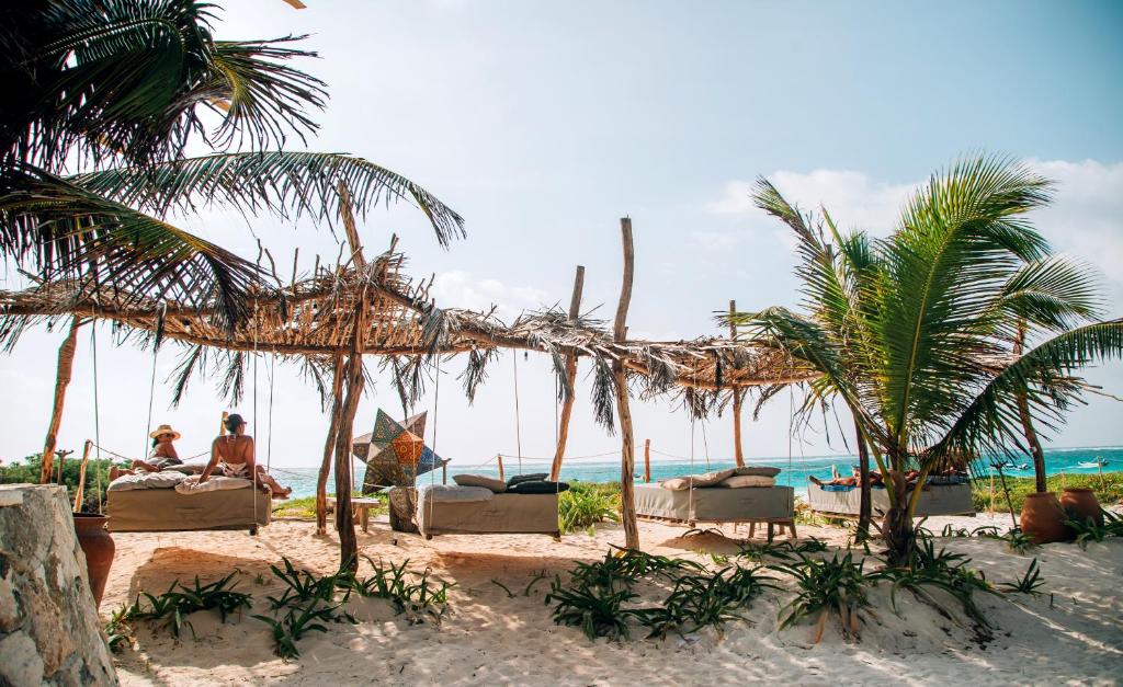 a beach with chairs and palm trees and the ocean at Ikal Tulum Hotel in Tulum
