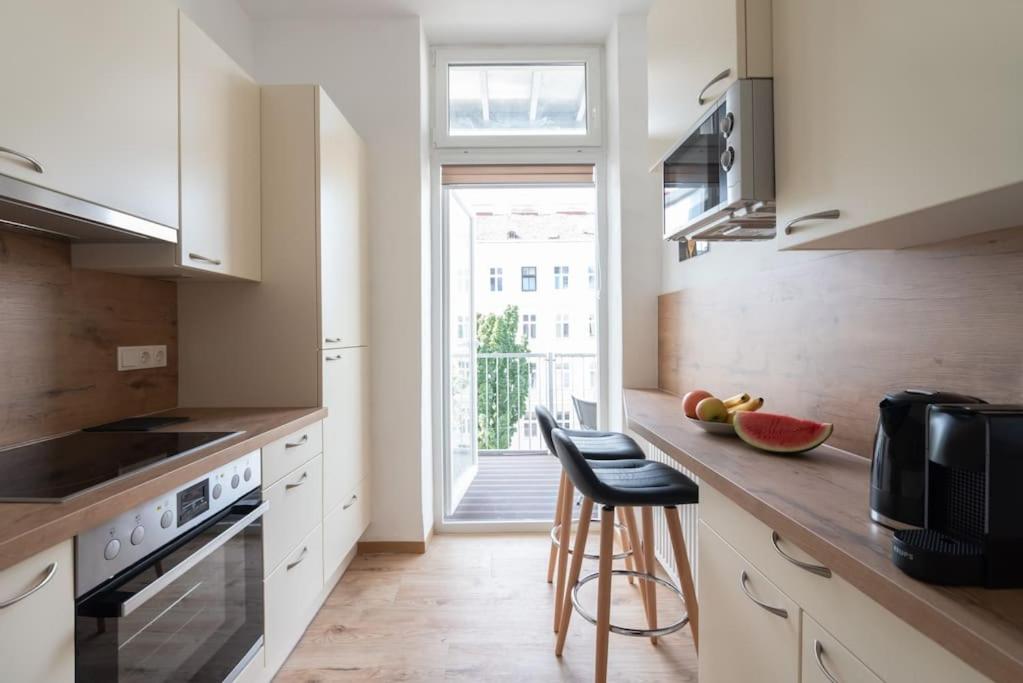 eine Küche mit weißen Schränken und einer Theke mit einem Fenster in der Unterkunft Lovely serviced apartment Vienna 3km to DT+Balcony in Wien