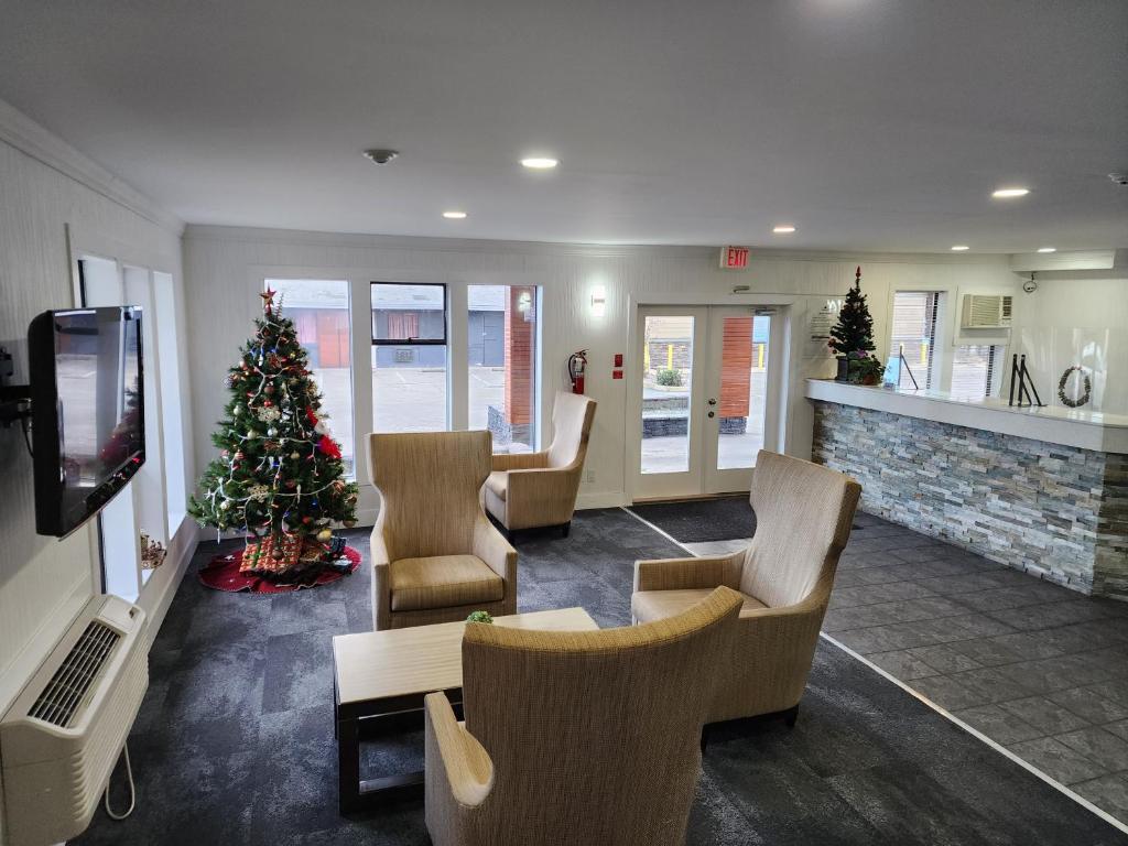 ein Weihnachtsbaum in einem Wartezimmer mit Stühlen und ein Zimmer mit Kamin in der Unterkunft Alpine Inn Abbotsford in Abbotsford