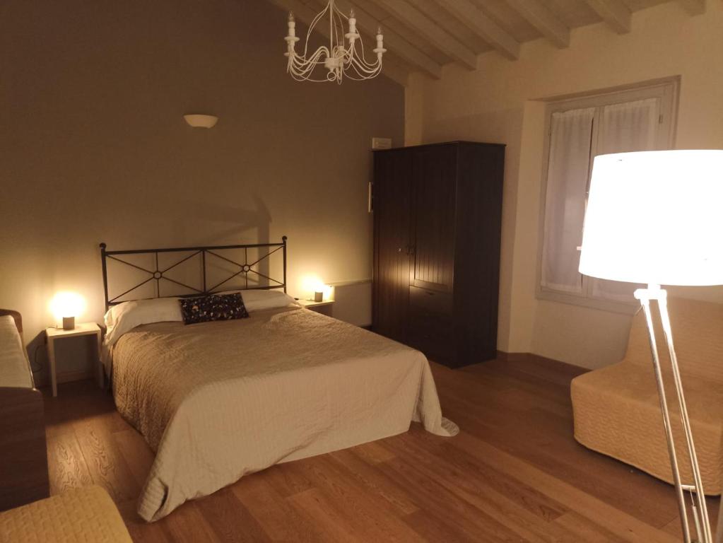 1 dormitorio con cama, lámpara y silla en Relais La Rocca Solferino, en Solferino