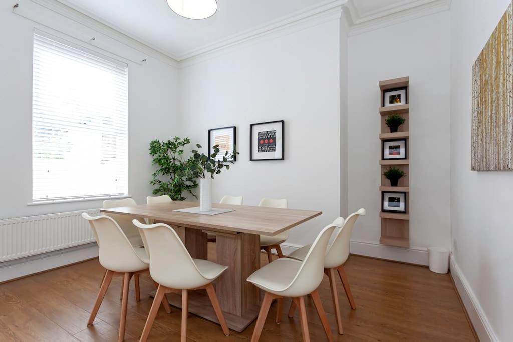 a dining room with a wooden table and white chairs at Spacious Comfortable house close to Etihad+parking in Manchester