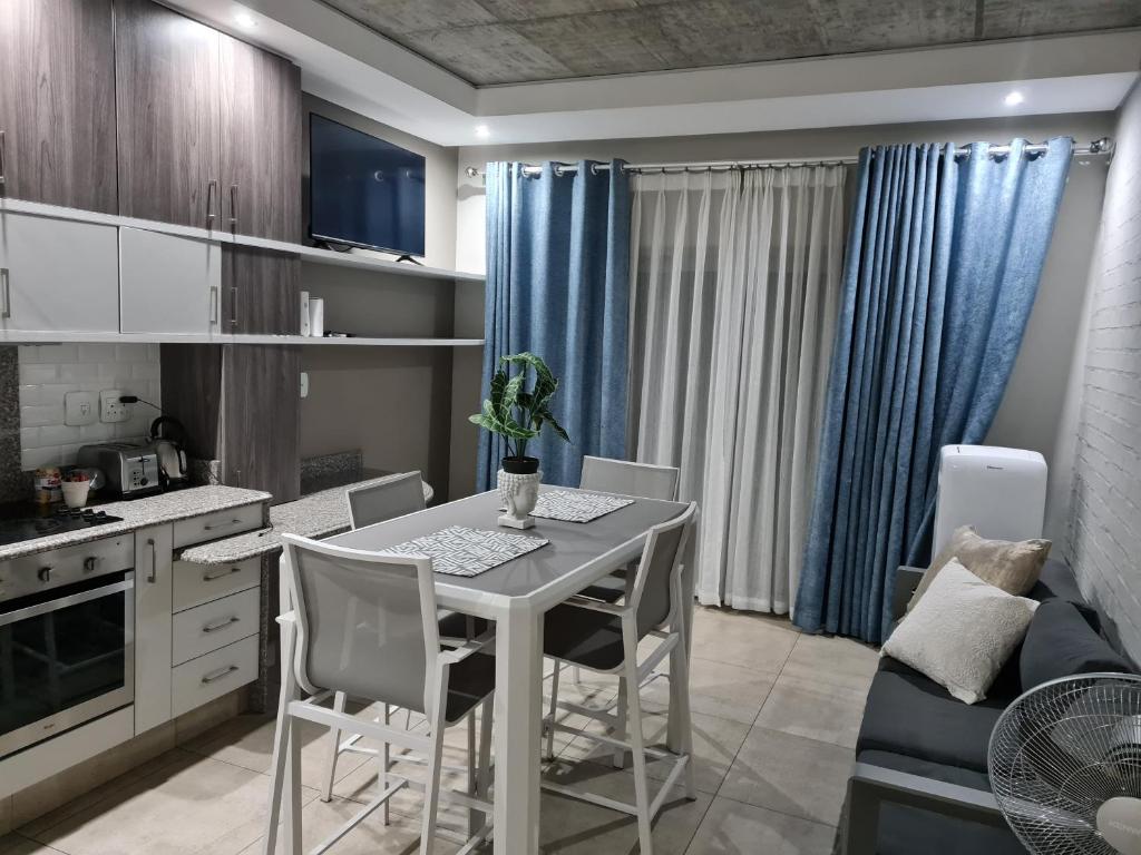 a kitchen and dining room with a table and chairs at Stunning City Living at Loftus in Pretoria