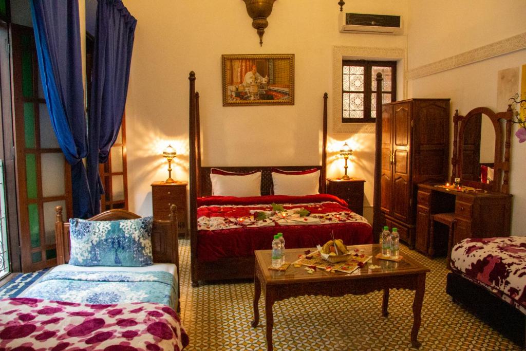a bedroom with two beds and a table and a couch at Riad Baba in Fez