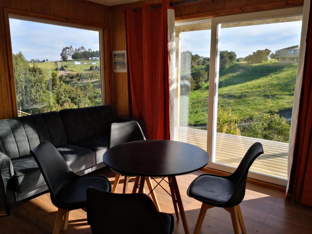 a living room with a table and chairs and a couch at Cabañas Mirador Los Avellanos in Castro