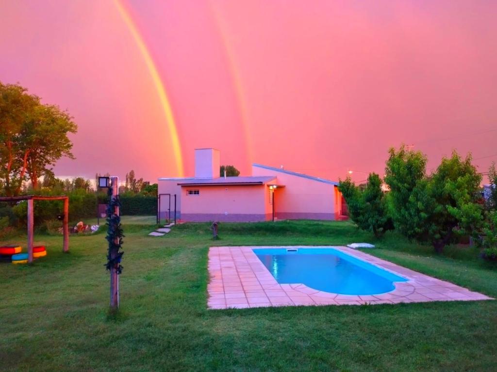 un arco iris sobre un patio trasero con una piscina y una casa en Casa Los Duraznos en San Rafael