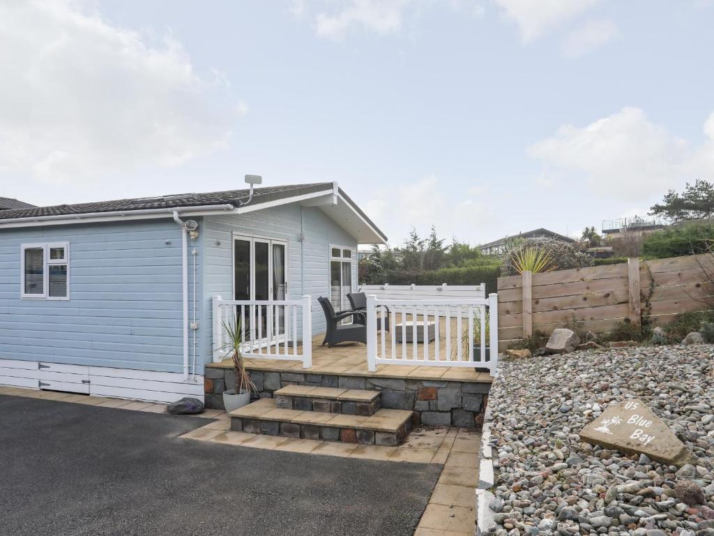 a blue tiny house with a porch and stairs at The Warren U5 in Abersoch