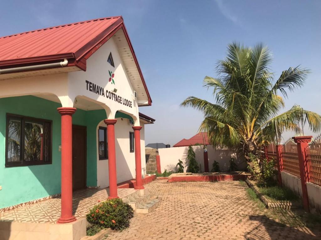 a building with a red roof and a palm tree at Temaya Cottage Lodge in Tamale