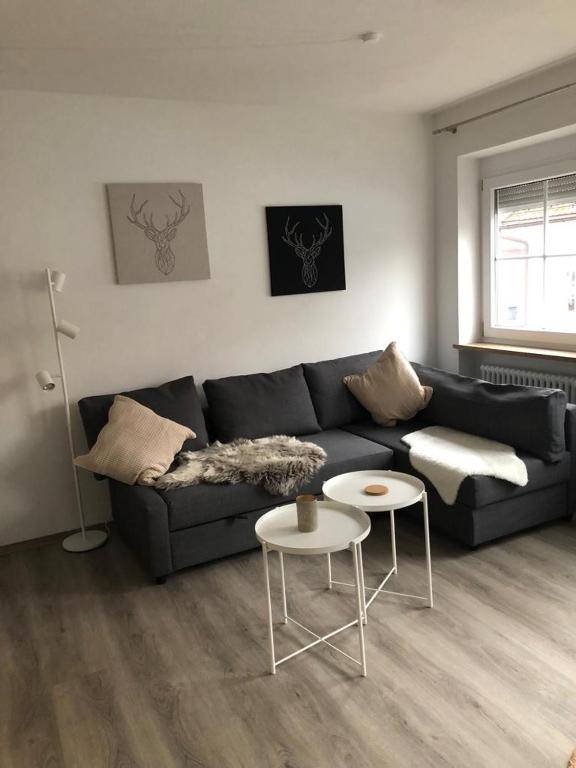 ein Wohnzimmer mit einem schwarzen Sofa und 2 Tischen in der Unterkunft Sonthof City in Sonthofen